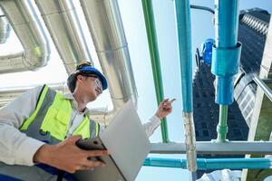 Industrial engineer adjusting pipeline valve with radio communication on construction site. Engineer on urban construction site using radio to coordinate with team on a sunny industrial rooftop. photo