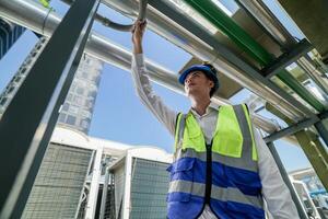 Industrial engineer adjusting pipeline valve with radio communication on construction site. Engineer on urban construction site using radio to coordinate with team on a sunny industrial rooftop. photo