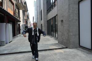 ASian man is dancing in hip hop style at outdoor space. Professional solo dancer is performing in public area. photo