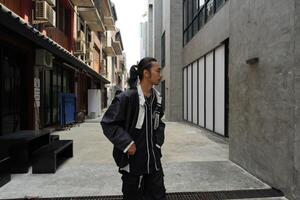 ASian man is dancing in hip hop style at outdoor space. Professional solo dancer is performing in public area. photo