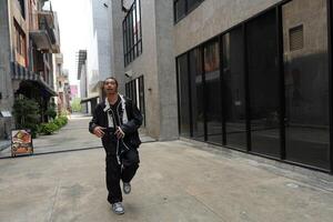 ASian man is dancing in hip hop style at outdoor space. Professional solo dancer is performing in public area. photo