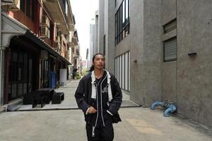 ASian man is dancing in hip hop style at outdoor space. Professional solo dancer is performing in public area. photo