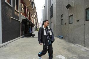 ASian man is dancing in hip hop style at outdoor space. Professional solo dancer is performing in public area. photo