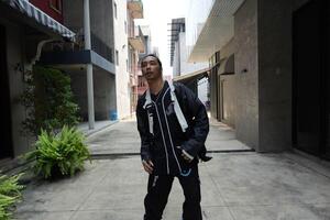 ASian man is dancing in hip hop style at outdoor space. Professional solo dancer is performing in public area. photo
