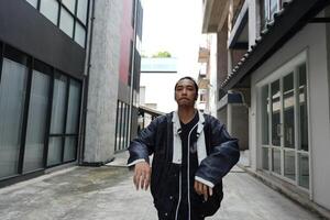 ASian man is dancing in hip hop style at outdoor space. Professional solo dancer is performing in public area. photo