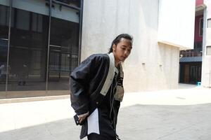ASian man is dancing in hip hop style at outdoor space. Professional solo dancer is performing in public area. photo