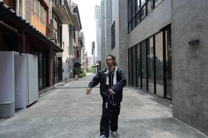 ASian man is dancing in hip hop style at outdoor space. Professional solo dancer is performing in public area. photo