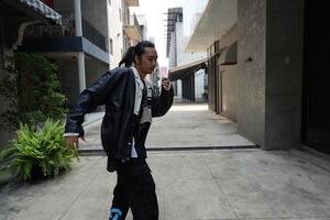 ASian man is dancing in hip hop style at outdoor space. Professional solo dancer is performing in public area. photo