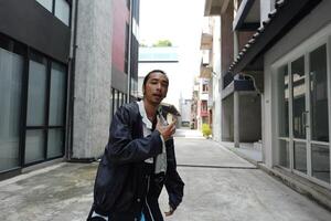 ASian man is dancing in hip hop style at outdoor space. Professional solo dancer is performing in public area. photo