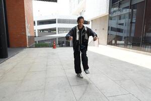 ASian man is dancing in hip hop style at outdoor space. Professional solo dancer is performing in public area. photo