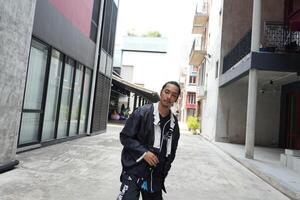 ASian man is dancing in hip hop style at outdoor space. Professional solo dancer is performing in public area. photo