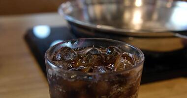 Hot and cold comparison in the foreground dark carbonated drink with ice in the background boiling water video
