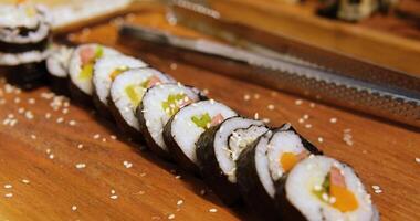 Sushi with vegetables Close-up of professional chef's hands rolling a sushi roll on seaweed mat video