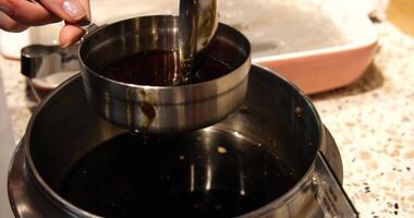 Pour soy sauce from a ladle shows anonymous hibachi chef hands serving yum yum sauce with a ladle into sauce containers on a table. video