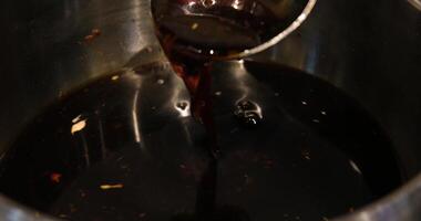 Pour soy sauce from a ladle Chef pours ladle of dark sauce over rice noodles in skillet, pan filled with steaming rice sticks get doused in soy sauce, slow motion close up 4K video
