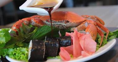 Sushi with crabs pour soy sauce over a plate of delicious rolls on a background of crab video