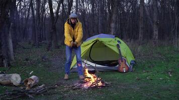 komisch Kerl Tänze in der Nähe von ein Zelt und ein Lagerfeuer im das Wald. Reise Konzept video