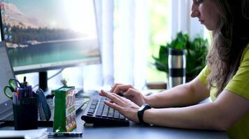 Hands on the keyboard close-up, work remotely from home. A woman is typing on a keyboard surrounded by home flowers, a cozy atmosphere. Distance learning, online learning and computer work video