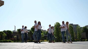 Pose for a photo Four pairs of people stand in jeans and white T-shirts with their backs to each other waiting for the dance photo shoot look into the frame take a photo video