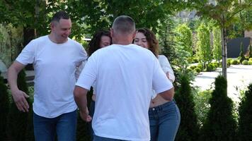 Cheerful family dancing in nature. Learn bachata dance steps. Two men and women dancing, hugging, posing, having fun, trying to repeat the movement of professional Latin American dance video