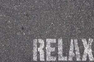 Road asphalt texture. Bitumen structure with painted relax word. photo