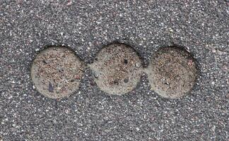 Road asphalt texture. Bitumen structure with 3 holes. photo