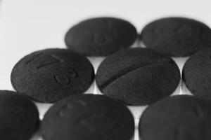 Black Medicine Tablets Handful. Pharmacy Pills on Isolated Background. Macro Closeup. photo