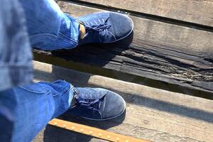 The feet of a man stand on an unstable wooden bridge. photo