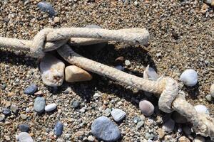 Rope with stone on sand beach photo