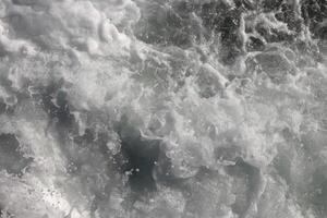 Marine aqua motion surface background. Outdoor water froth swirls backdrop. Sea wave foam texture. photo