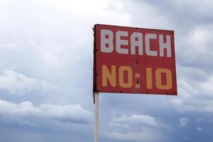 Red beach number sign near sea. photo