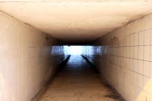 A light in the end of a tunnel. Underpass with white tiles. photo