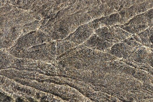 Aqua dynamic texture. Clear stream with sand on background. photo