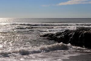 Seascape with rock and sunlight on shoreline. photo