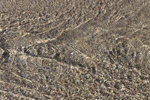 Aqua motion texture. Clear stream with sand on background. photo