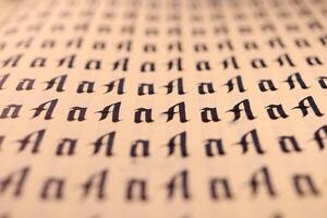 Calligraphic letter A learning skills paper page. Calligraphy letters A background. Lettering practice writing worksheet. Handwriting symbol filling pattern. photo