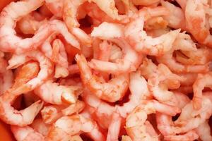 Boiled peeled shrimps meat texture. Prawns snack filling background. photo