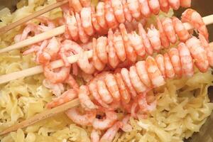 Rows of peeled boiled shrimp with macaroni. Many cooked prawns with pasta background. photo
