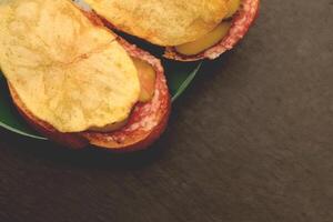 Sandwiches with bread slices cheese salt cucumber and crisps on green saucer. Filling background. photo