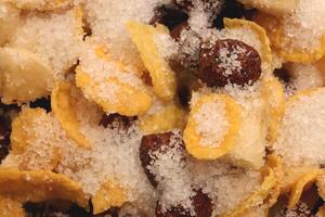 Cornflakes with chocolate balls sliced banana and sugar. Filling background. Macro close-up. photo