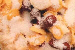 Cornflakes with chocolate balls sliced banana and sugar. Filling background. Macro close-up. photo
