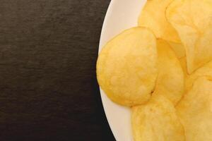 Crisp on the plate on black stone background. photo