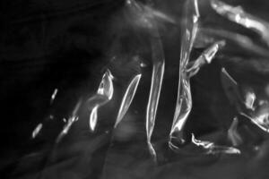 Drawing of the glowing rays of the sun on crumpled cellophane. Black and white. Filling background. photo