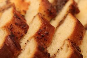 Sweet swirling roll bun with poppy and raisins. Filling background. Macro closeup. photo