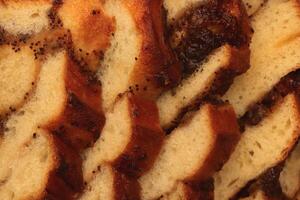 Sweet swirling roll bun with poppy and raisins slices. Filling background. Macro closeup. photo