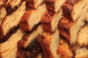 Sweet swirling roll bun with poppy and raisins slices. Filling background. Macro closeup. photo