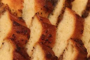 Sweet swirling roll bun with poppy and raisins slices. Filling background. Macro closeup. photo