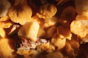 Cornflakes with chocolate sliced banana and milk in sun light. Filling background. Macro close-up. photo