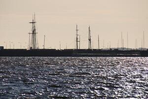 Silhouette of a sailing ship against the background of port piers on the shores of the Gulf of Finland photo