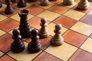 Chess Black and white pawns and rooks stand on a chessboard with figures on background. Wood game chessboard. background. Wood game chessboard. photo